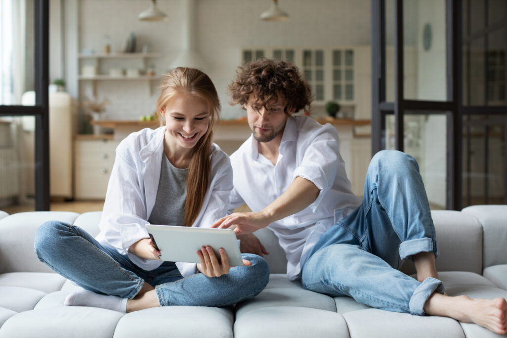 Young couple with digital tablet on cozy sofa, online shopping